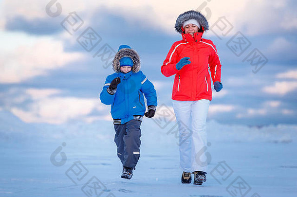 可爱的小男孩和他的妈妈在冰冷的海滩上