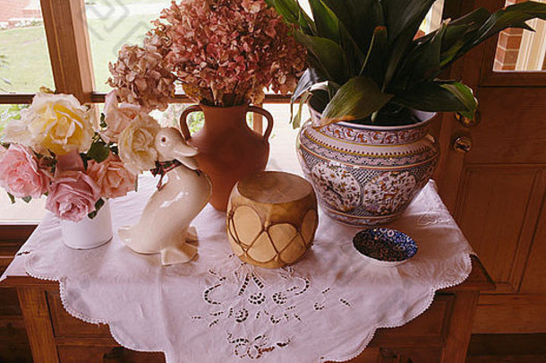 桌子的特写，盆中有鲜花花瓶和室内植物，用英国布制成