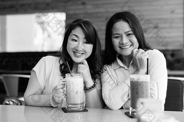 两个成熟的亚洲女人一起在咖啡馆里玩