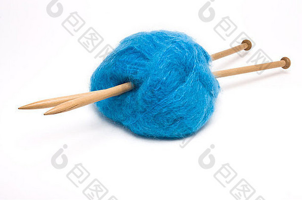 一个蓝色马海毛的大球，用大的木制针织针在白色的衬托下刺穿。