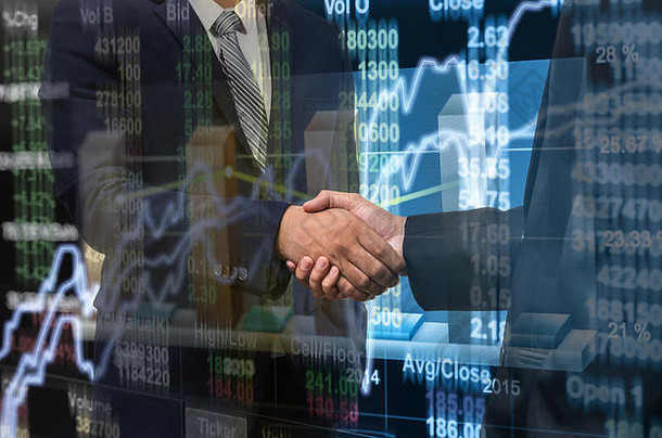 商人在股市图表上握手，在LED显示屏上特写股市交易数据，商业交易概念