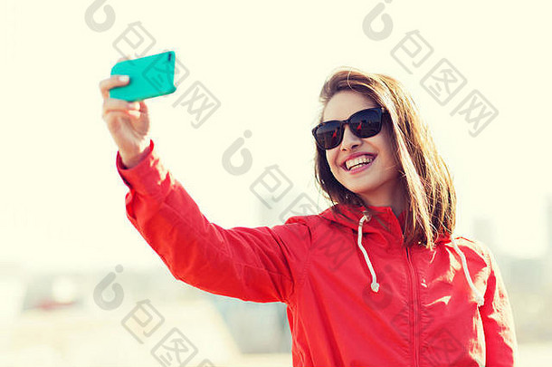 微笑的年轻女子用智能手机自拍