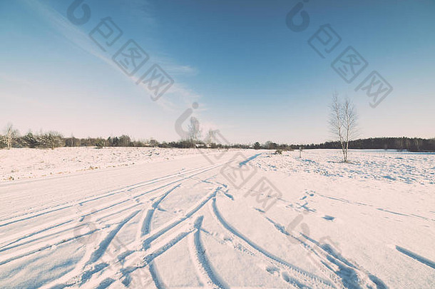 带轮胎标记和蓝天的冬季雪路-复古复古效果