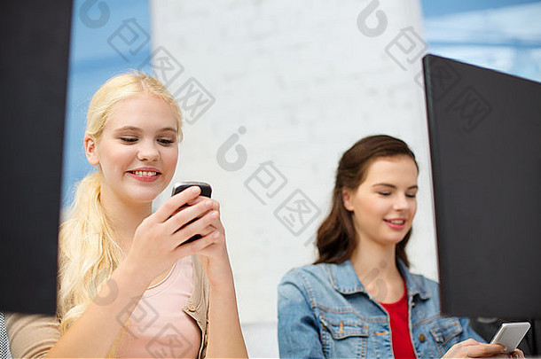 两名青少年在电脑课上使用智能手机