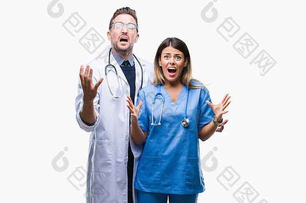 一对年轻的医生和外科医生在孤立的背景下疯狂地叫喊着，带着咄咄人的表情，举起手臂。挫败