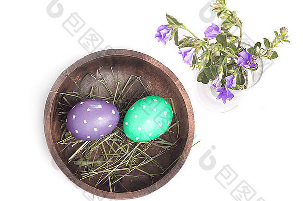 木制碗中的复活节彩蛋和白色背景上的花朵