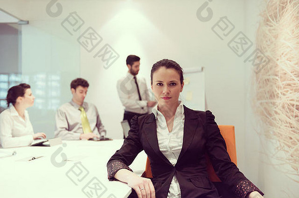 在现代光明创业公司办公室内部，一位年轻的女商人在会见usineg笔记本电脑时，模糊了背景中的一群人，在他们的笔记本电脑上做笔记