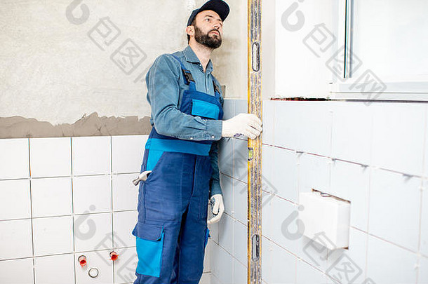 工人蓝色的统一的检查水平安装白色陶瓷瓷砖浴室