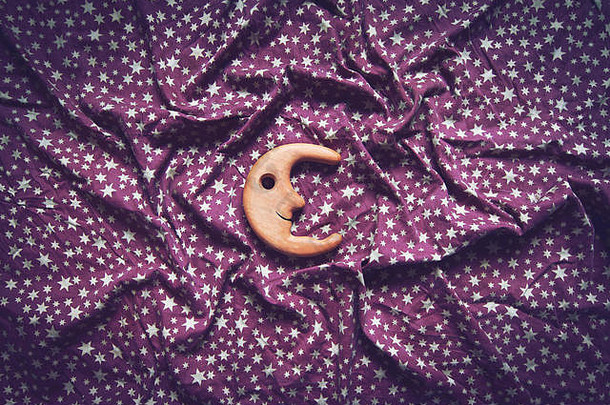 俯视概念褶皱背景纹理紫色纺织桌布，中间有白色星星和木制玩具月亮