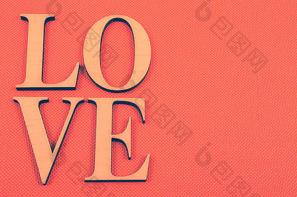 在橙色背景上书写的构成“爱”一词的木制字母