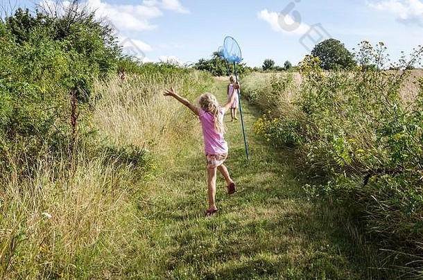在绿色的乡村里，孩子手里拿着网在<strong>抓蝴蝶</strong>