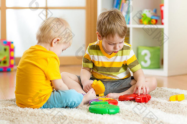 孩子们小男孩在托儿所玩五颜六色的拼图游戏