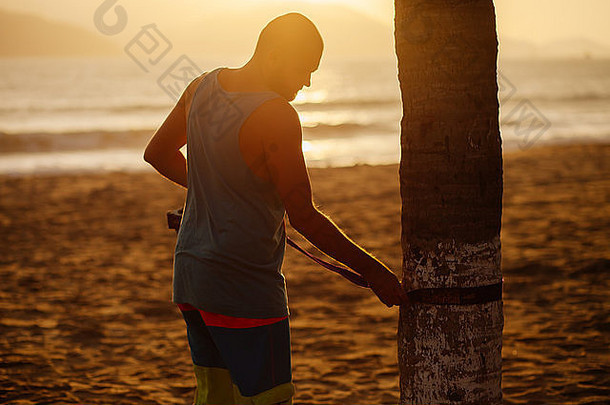 一个十几岁的男子在日出时在海滩<strong>上架</strong>起了一条松驰线