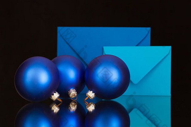 黑色玻璃桌上的蓝色信封和圣诞装饰