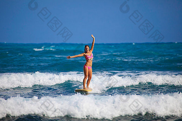 穿着粉色比基尼和花蕾的美丽少女在夏威夷冲浪