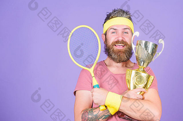 赢得我参加的每一场网球比赛。网球运动员赢得冠军。运动员手持网球拍和金杯。留着大胡子的时髦男人穿运动装。成功和成就。赢得网球比赛。