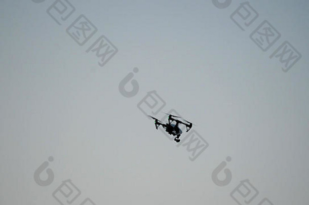 带摄像头的黑色无人机四架直升机飞越蓝天。天空中黑色的嗡嗡声。在空中飞行的四翼无人机，装有数码相机，用于视频和<strong>照片制作</strong>