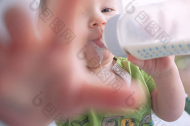 婴儿从奶瓶里喝牛奶。控制住自己。甜蜜有趣