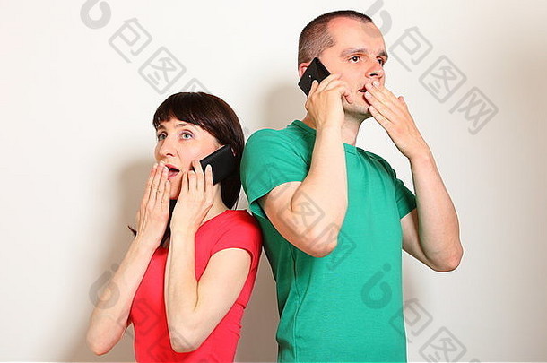 震惊的女人和男人在用手机通话时收到了一条意想不到的信息，双手捂住嘴，脸上的表情