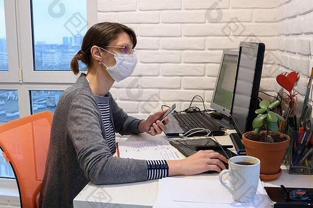 一个戴着医用面罩的生病女孩在自我隔离中远程工作