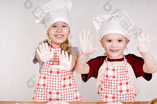 两个孩子戴着厨师帽，手掌露出来