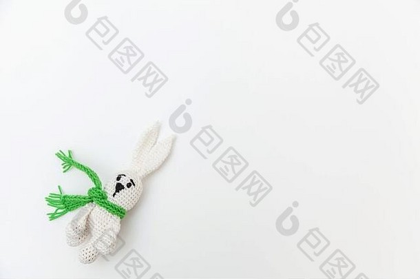 简单简约的设计，白色背景上隔离着绿色围巾的<strong>玩具</strong>兔子。儿童保育材料家庭观念。平面俯视图空间