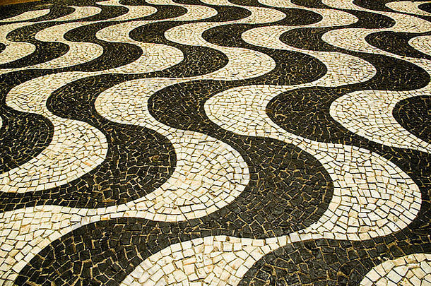 黑白马赛克瓷砖在科帕科巴纳人行道上形成弯曲的图案。巴西里约热内卢