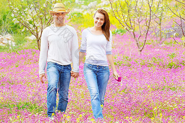 幸福的情侣漫步户外，美丽的春天花园，粉色的花坛，浪漫的约会，爱情的概念