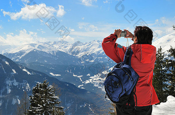 高级女人背包持有相机采取图片冬天山后视图