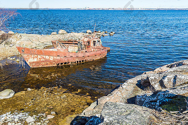 瑞典布莱金海岸两艘锈迹斑斑的沉船，背景是卡尔斯克罗纳镇。天气晴朗，海面平静。