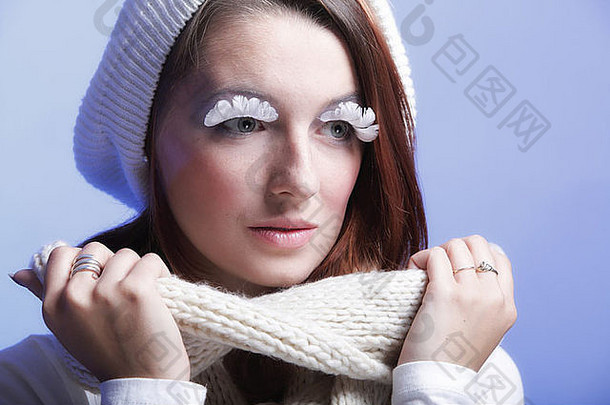 冬季时尚美女穿着保暖服装时尚创意化妆假长白眼睫毛蓝色背景