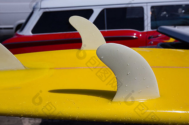 黄色冲浪板龙骨鳍在加利福尼亚州的背景中详述了红色复古汽车