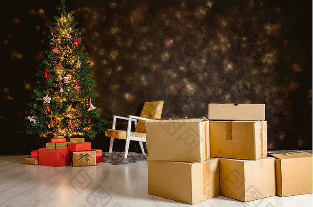 搬进新家过圣诞节。重点放在纸板箱和装饰过的圣诞树上，背景是礼物