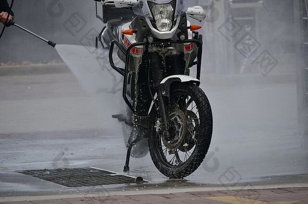 摩托车洗车使摩托车更干净。一系列照片一个骑自行车的人在洗车场洗他的摩托车。