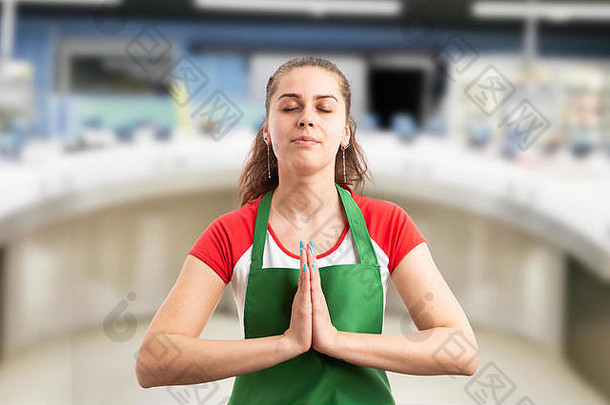 超市女员工合掌默想或祈祷，闭上眼睛，这是一个充满希望的概念