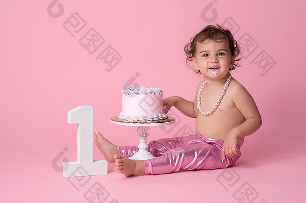 快乐一年婴儿女孩坐着生日蛋糕穿粉红色的紧身裤字符串珍珠结霜下巴