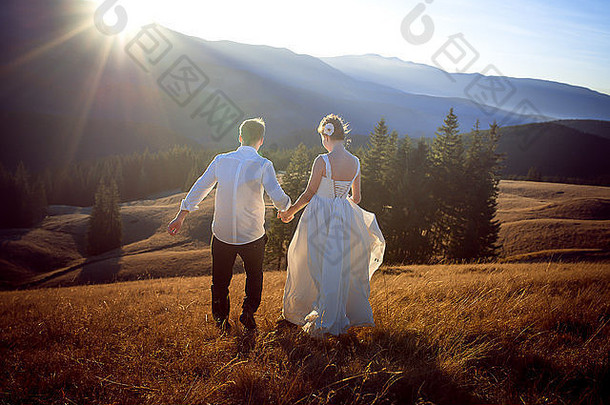 迷人的新婚夫妇走在小路上。阿尔卑斯山脉背景。蜜月