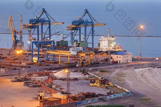 乌克兰马里乌波尔夜间海上商业港口。工业观点。位于港口的带工作起重机桥架的货运船