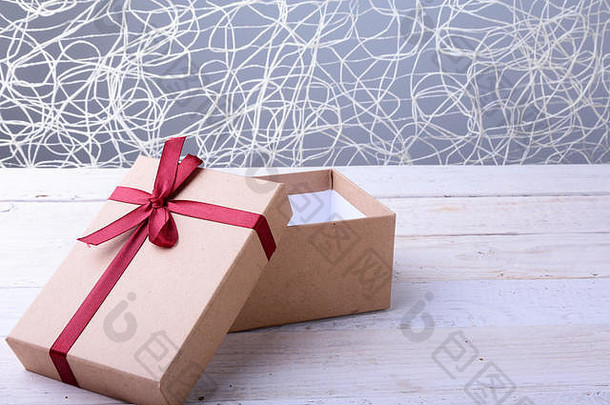打开木制背景上带有蝴蝶结的礼品盒。<strong>圣诞</strong>装饰。