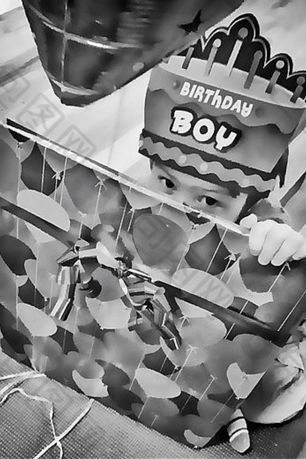 一个害羞的生日男孩戴着一顶生日帽，从他包装好的礼物后面向外窥视。