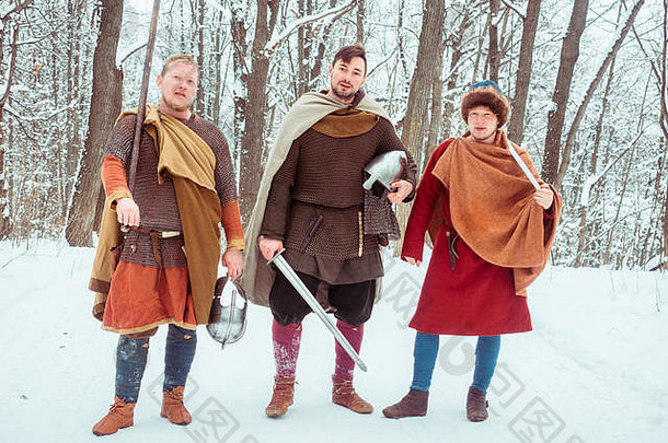 一群手持盾牌、剑、矛的中世纪武装战士在冬季森林中