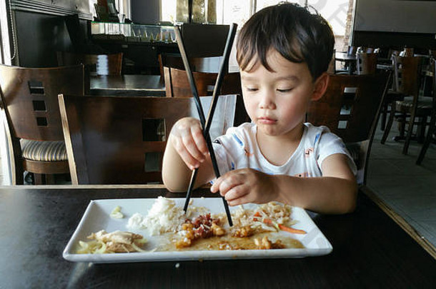 可爱<strong>的</strong>年轻<strong>的</strong>中国人高加索人男孩学习筷子餐厅