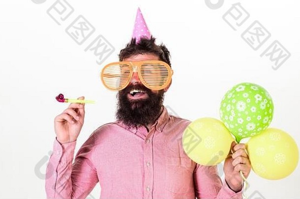 脸上留着胡须的男子手持白色背景的气球。党的概念。穿着巨型太阳镜庆祝生日的时髦人士。戴派对帽、吹派对号角的家伙在庆祝。