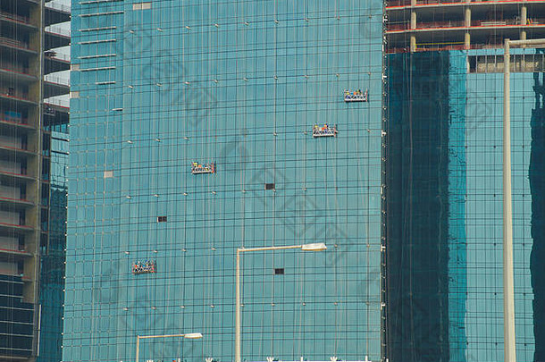 工人们正在新摩天大楼的玻璃墙