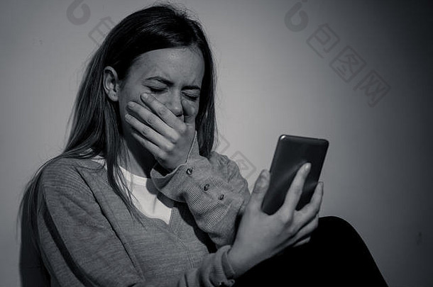 悲伤绝望的年轻女孩在智能手机上遭受在线<strong>欺凌</strong>和骚扰，晚上坐在床上感到孤独和绝望