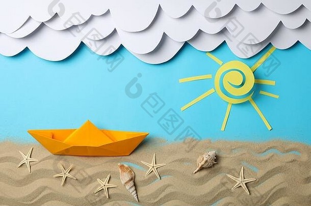 纸云，太阳和船，蓝色背景上有海星的沙子。假期