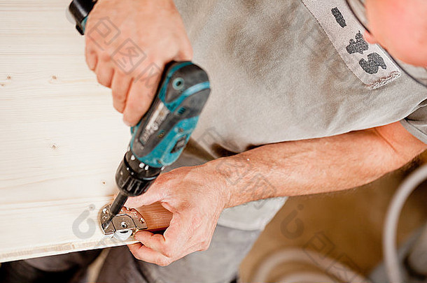 关注木匠在家具部件上使用钻头进行的螺丝操作
