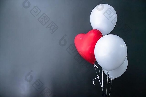 红色心形气球和黑色背景上的白色圆形气球。情人节、节日、爱情。