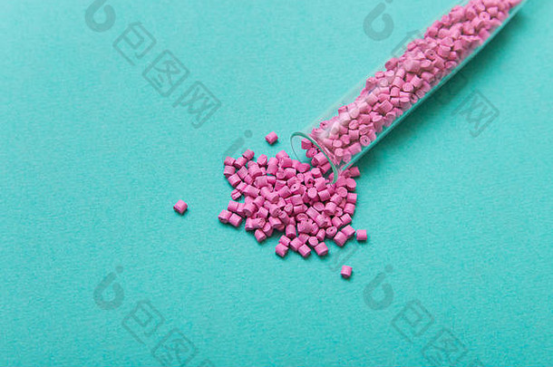 塑料球团矿粉红色的塑料颗粒管绿松石背景塑料生材料