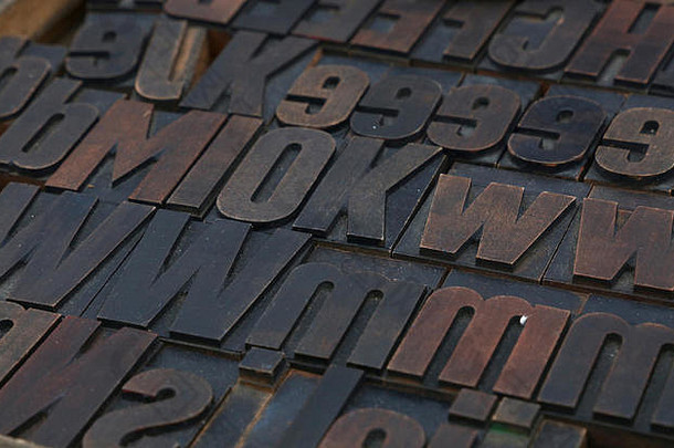 旧的深色木制复古古董胶印活版印刷块被油漆弄脏，混合字母，特写，高角度视图